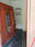 Una puerta de madera con una celosía metálica decorativa y un objeto tejido colgando debajo.
