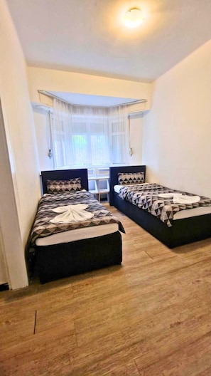 A room with two beds, a window with sheer curtains, and a ceiling light. - Villa Birkenfeld (Birkenfeld)