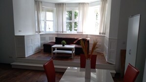 A modern living room with a dining area, large windows, and a view of the outdoors. - Villa Birkenfeld (Birkenfeld)