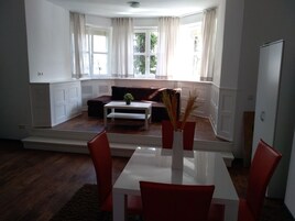 Una sala de estar moderna con comedor, ventanas amplias y vistas al exterior.