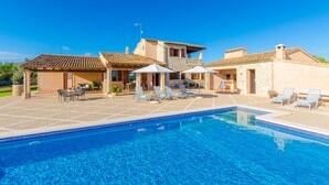 A poolside area with a clear blue pool, lounge chairs, and a covered patio. - NA MAIANS - Villa with private pool in Canyamel. Free WiFi (Canyamel)