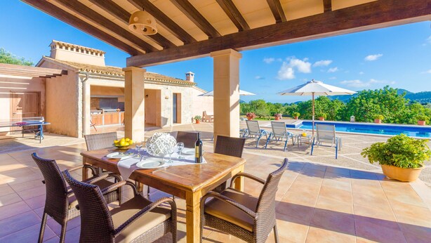 A covered outdoor patio with a dining table set for two, surrounded by wicker chairs. - NA MAIANS - Villa with private pool in Canyamel. Free WiFi (Canyamel)