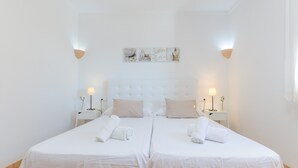A double bed with white linens, two bedside tables with lamps, and a wall-mounted artwork above the bed. - NA MAIANS - Villa with private pool in Canyamel. Free WiFi (Canyamel)