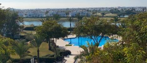 A pool area with a view of a lake and buildings in the background.