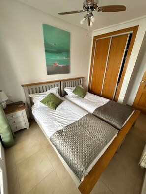 Un letto matrimoniale con testiera, un comodino con lampada, un quadro appeso al muro e una porta in legno.