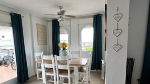 Et spiseområde med et bord, stole, en loftventilator og udsigt gennem et vindue.