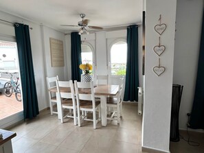 Zona pranzo con tavolo e sedie, una ventola a soffitto e vista dalla finestra.
