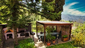 A covered outdoor seating area with a table and chairs, surrounded by potted plants and a stone pathway. - Nice Apartment in a splendid quiet area - seaview (Castiglione Chiavarese)