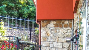 A stone building with a staircase leading to a door, surrounded by potted plants and flowers. - Nice Apartment in a splendid quiet area - seaview (Castiglione Chiavarese)