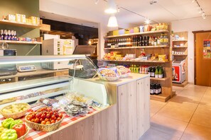 A grocery store interior with a deli counter, shelves stocked with various products, and a refrigerated display. - Hapimag Resort Sonnleitn (Hermagor-Pressegger See)