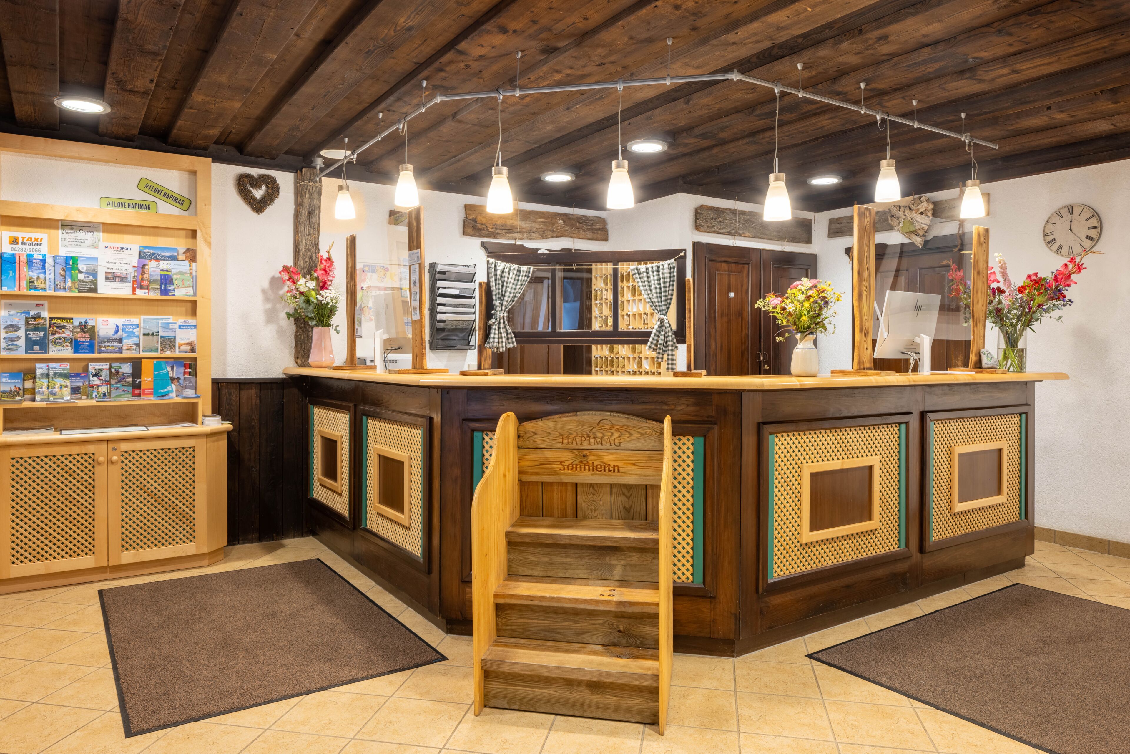 A reception area with a wooden counter, bookshelves, a heart-shaped decoration, and a clock on the wall.