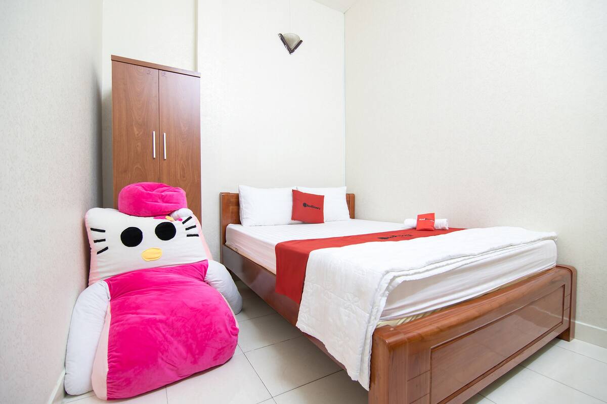 Et hotelværelse med en seng, et klædeskab og en Hello Kitty pøllepude.