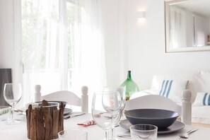 A dining table set with clear glassware, a dark bowl, and a green bottle. - Marina Boutique Duplex (Sant Antoni de Calonge)