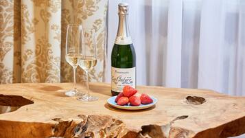Una mesa de madera con una botella de champán, dos copas y un plato de fresas.