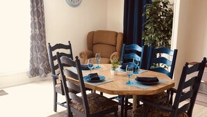 A dining area with a round wooden table, black chairs, and a blue clock on the wall. - Peaceful Country Cozy home semi secluded minutes to North end of Lake Ouachita. (Jessieville)