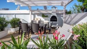 Un patio al aire libre con una parrilla, asientos y plantas en macetas.