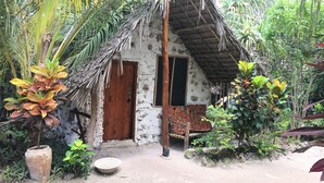 Eine rustikale Hütte mit einem Reetdach, einer Holztür und einem kleinen Fenster.