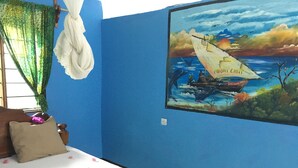 Ein Schlafzimmer mit einem Bett, einem Bild eines Bootes an der Wand und einem Fenster mit Vorhängen.