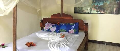 Uma cama com dossel, almofadas florais e um quadro na parede.