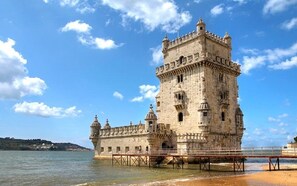 Uma torre de pedra histórica com varanda, com vista para um corpo de água.