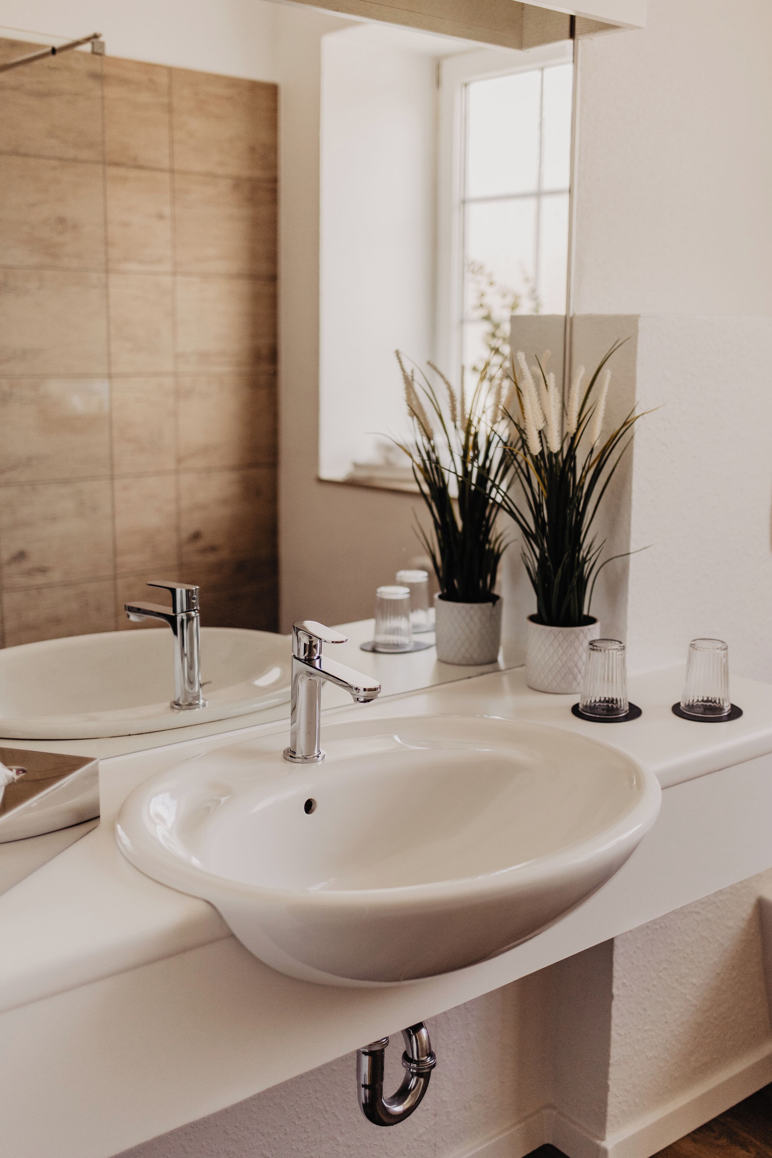 A bathroom with two sinks, a mirror, and a wooden wall.