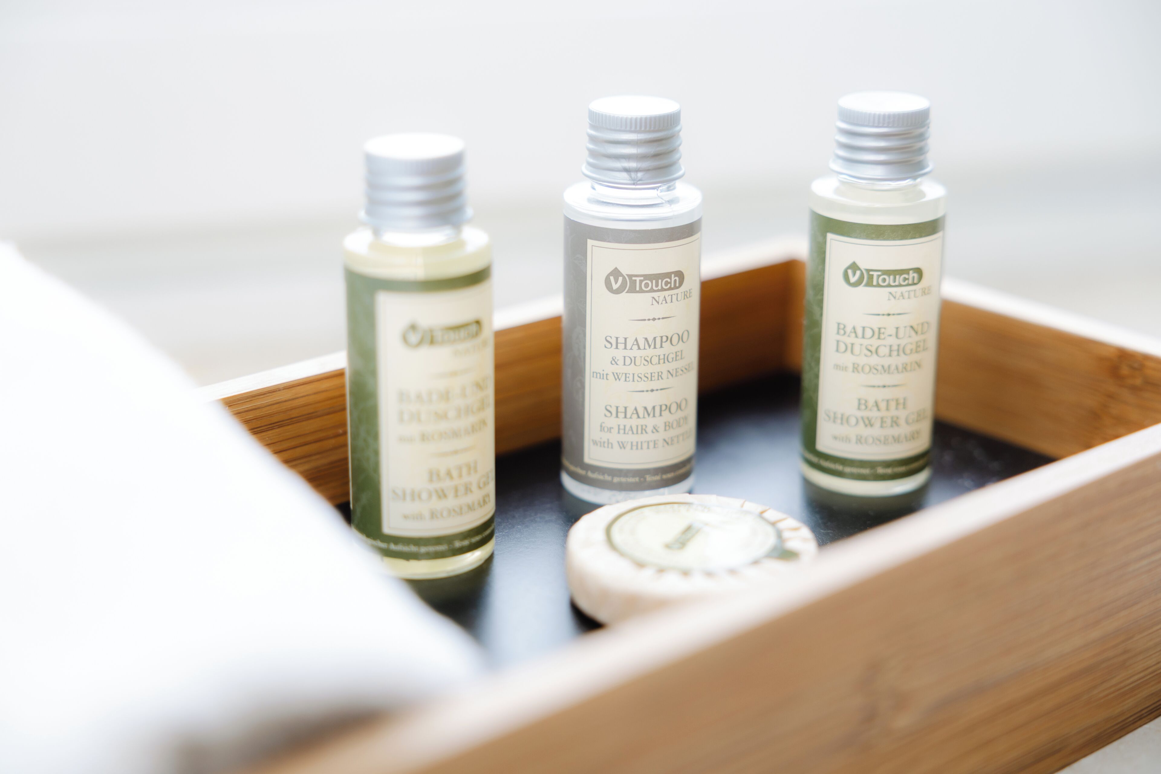 Three bottles of Touch Nature shampoo and bath products in a wooden tray.