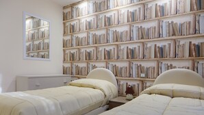 A bedroom with two beds, a bookshelf, a dresser, and a mirror.