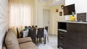 A compact living space with a dining area, a sofa, a dark wooden cabinet, and a television on a stand.