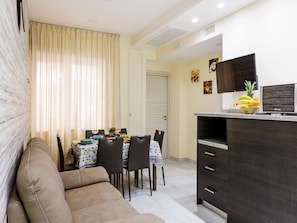 A compact living space with a dining area, kitchenette, and a sofa.