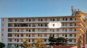 Un edificio residencial de varios pisos con balcones y techo plano.