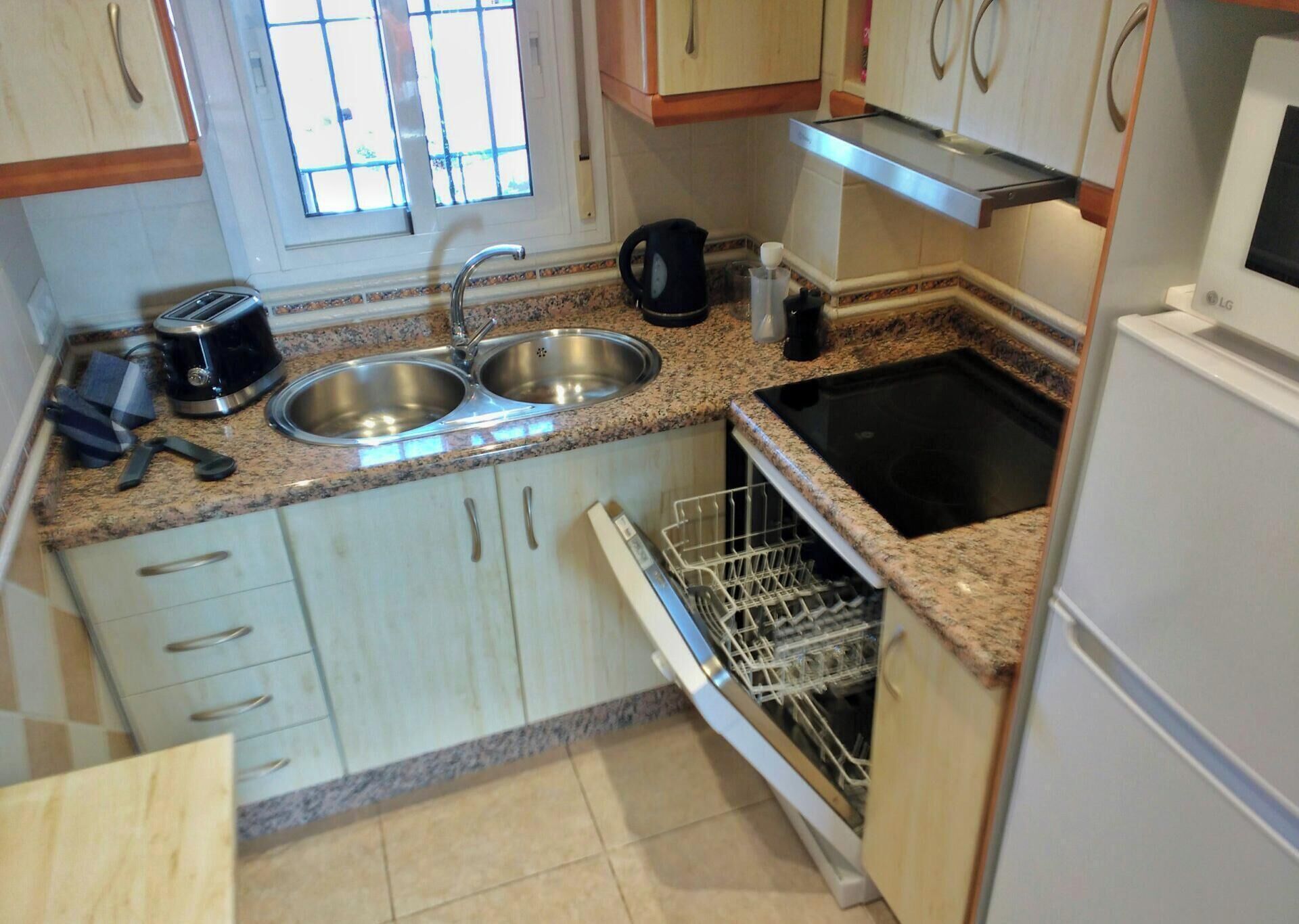 Eine Küche mit Granit Arbeitsplatten, Edelstahlspülen, einem Geschirrspüler und einer Mikrowelle.