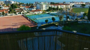 A residential area with a sports court, houses, and a view of the sea.