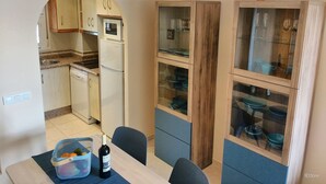 A compact kitchen with a refrigerator, microwave, and wooden cabinets.