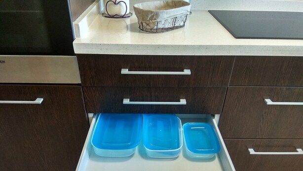 Een keuken met een lade waarin blauwe opbergboxen zitten.