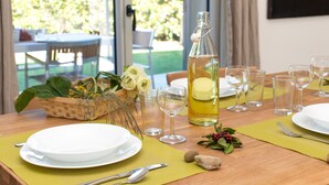 A dining table set with plates, cutlery, glasses, and a bottle of lemon water.