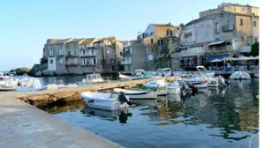 A marina with boats docked, a stone building with multiple stories, and a clear sky.