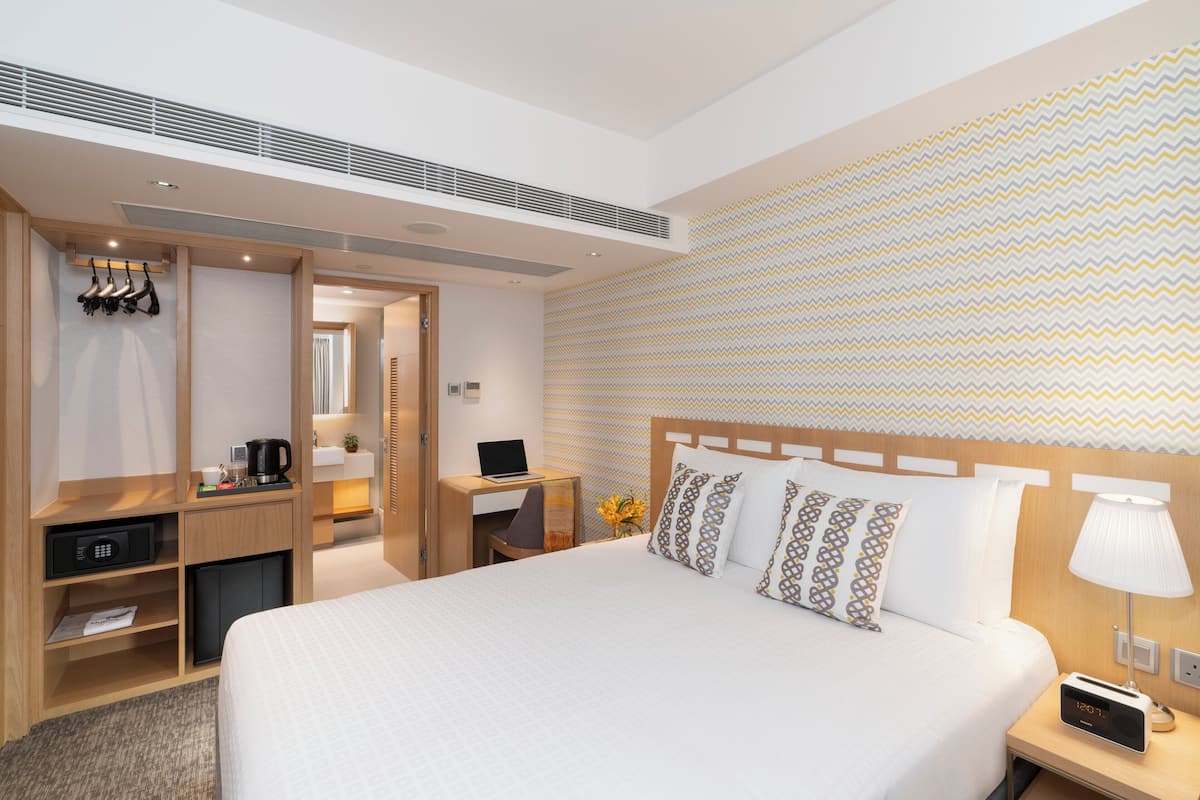 A hotel room with a large bed, a desk with a laptop, a microwave, and a coffee maker.