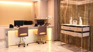 Un mostrador de recepción con dos sillas, una computadora y una planta.