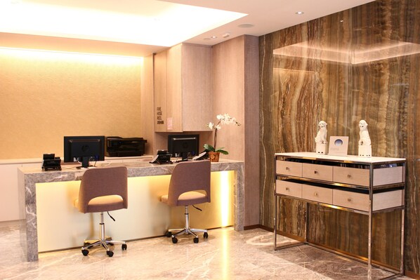 A reception desk with two chairs, a computer, and a plant.