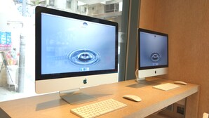 Dos computadoras Apple iMac sobre un escritorio de madera, con un teclado y un ratón.