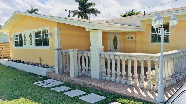 Une maison jaune avec un balcon blanc, un palmier et un lampadaire.