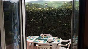 Un coin repas avec une table dressée pour deux personnes, une chaise blanche et un chapeau décoratif posé sur la table.