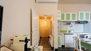 A compact kitchen with a coffee machine, a sink, and a microwave. A dining area with a table and chairs is visible.