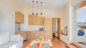 Una cocina moderna con armarios de madera, una mesa de comedor con superficie de vidrio e iluminación colgante.