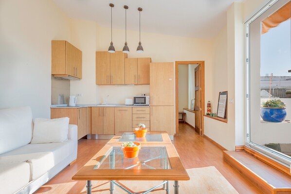 A modern kitchen with wooden cabinets, a glass-top dining table, and pendant lighting.