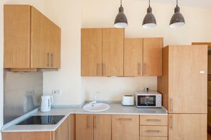 A kitchen with wooden cabinets, a sink, a kettle, a toaster, and a microwave.
