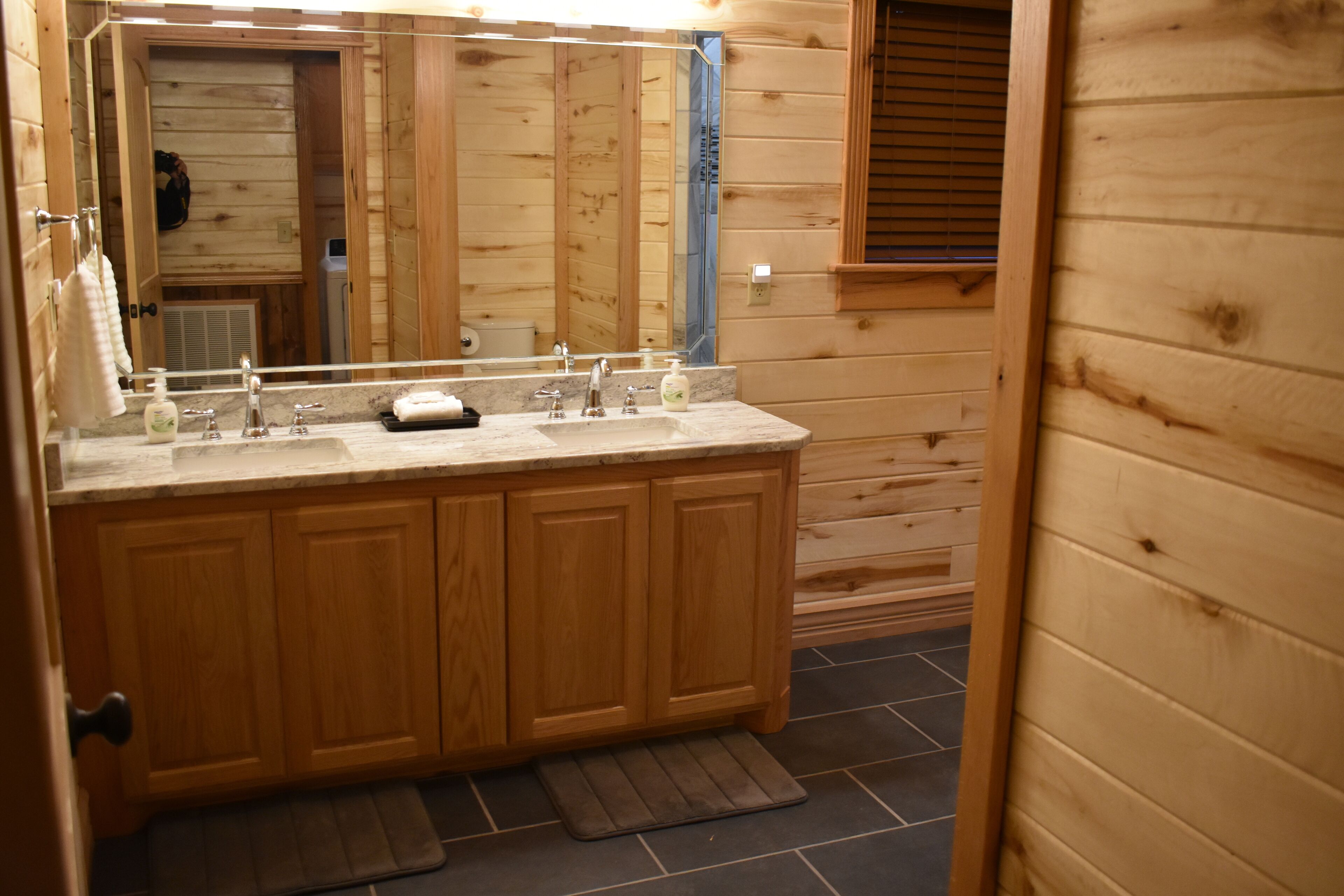 A wooden cabin bathroom with a wooden vanity, a large mirror, and a sink.