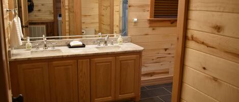 A wooden cabin bathroom with a wooden vanity, a large mirror, and a sink.