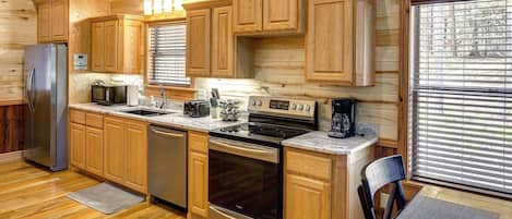 Una cocina con paneles de madera, refrigerador, microondas, estufa y lavavajillas.