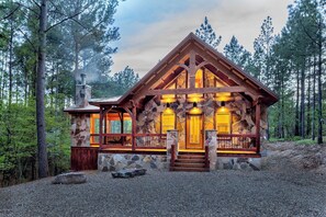A rustic cabin with a stone exterior, wooden beams, a porch, and a chimney emitting smoke. - Legends Lair-Mountain Hideaway, Woodburning Fireplace, Hot Tub, Jetted Tub🔥🌊🌲 (Broken Bow)